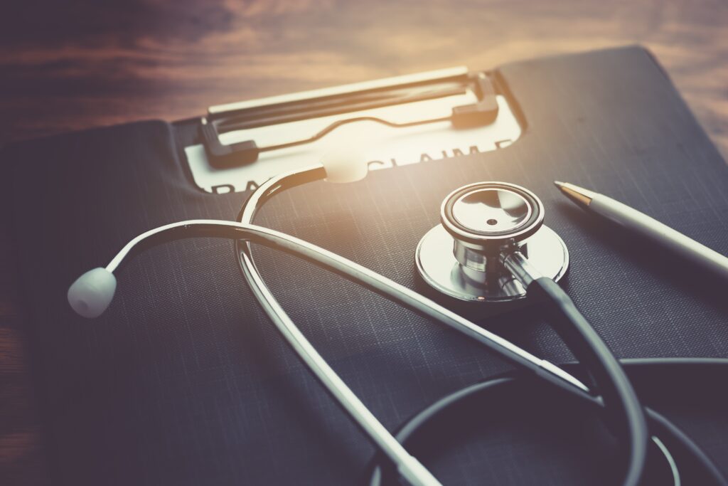 Estetoscopio y formulario sobre un escritorio, representando la gestión de un seguro médico privado.