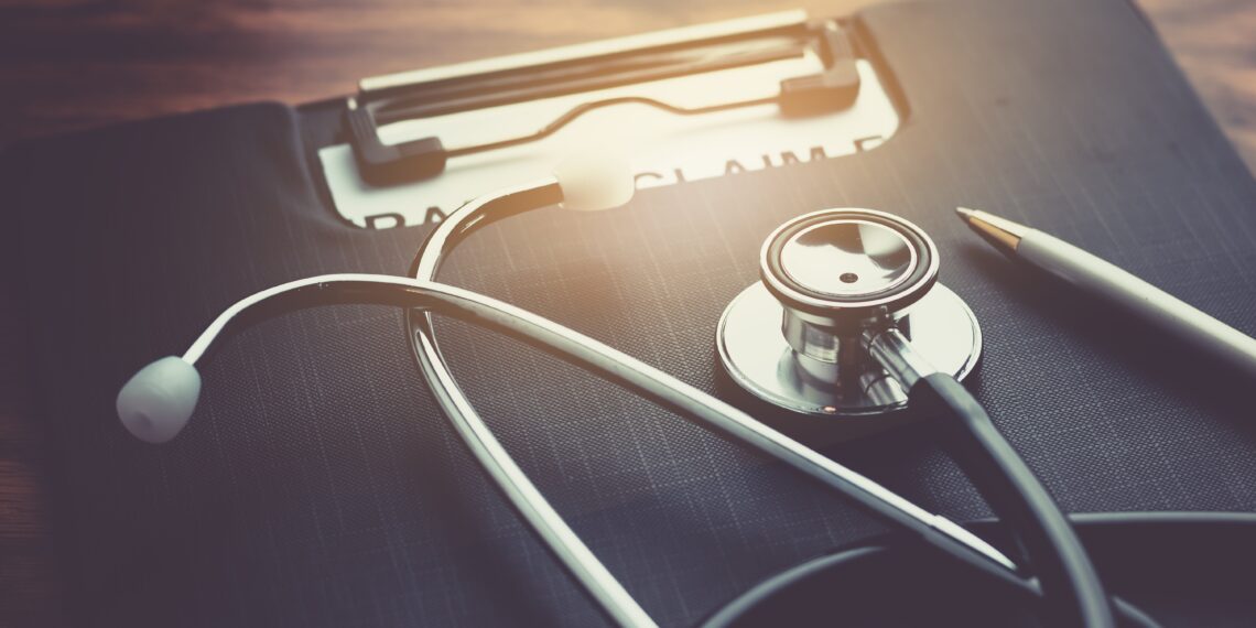 Estetoscopio y formulario sobre un escritorio, representando la gestión de un seguro médico privado.