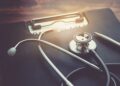 Estetoscopio y formulario sobre un escritorio, representando la gestión de un seguro médico privado.