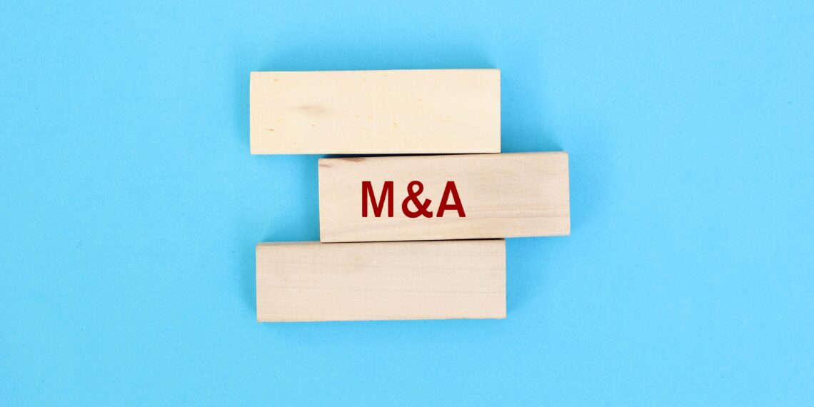 Concepto visual de fusiones y adquisiciones representado con bloques de madera y las siglas M&A, en referencia a la estrategia de crecimiento de TWFG Insurance.