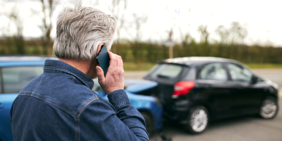 Hombre mayor llama por teléfono tras un choque entre dos autos, ilustrando la importancia del seguro de automóvil y la cobertura Green Card en caso de siniestro.