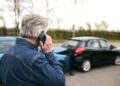 Hombre mayor llama por teléfono tras un choque entre dos autos, ilustrando la importancia del seguro de automóvil y la cobertura Green Card en caso de siniestro.