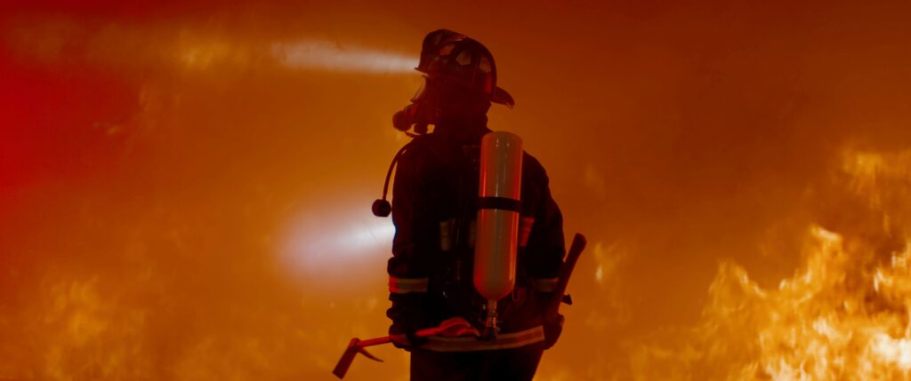 Bombero con equipo completo enfrenta incendio forestal, riesgo asegurado por pólizas contra desastres