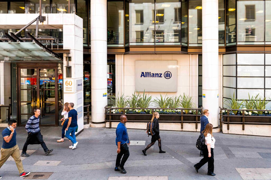 Fachada principal de Allianz House en Londres con transeúntes caminando frente al edificio de la aseguradora.