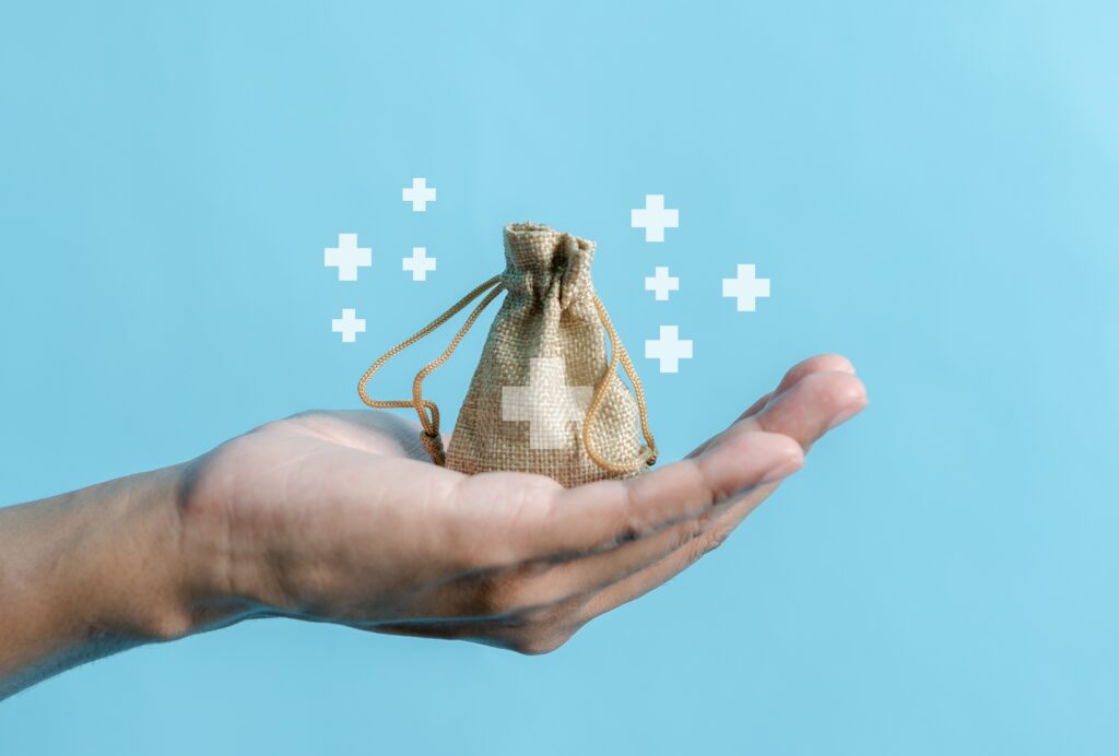 Mano sostiene bolsa de tela con símbolo de salud, ilustrando conceptos de costos médicos.