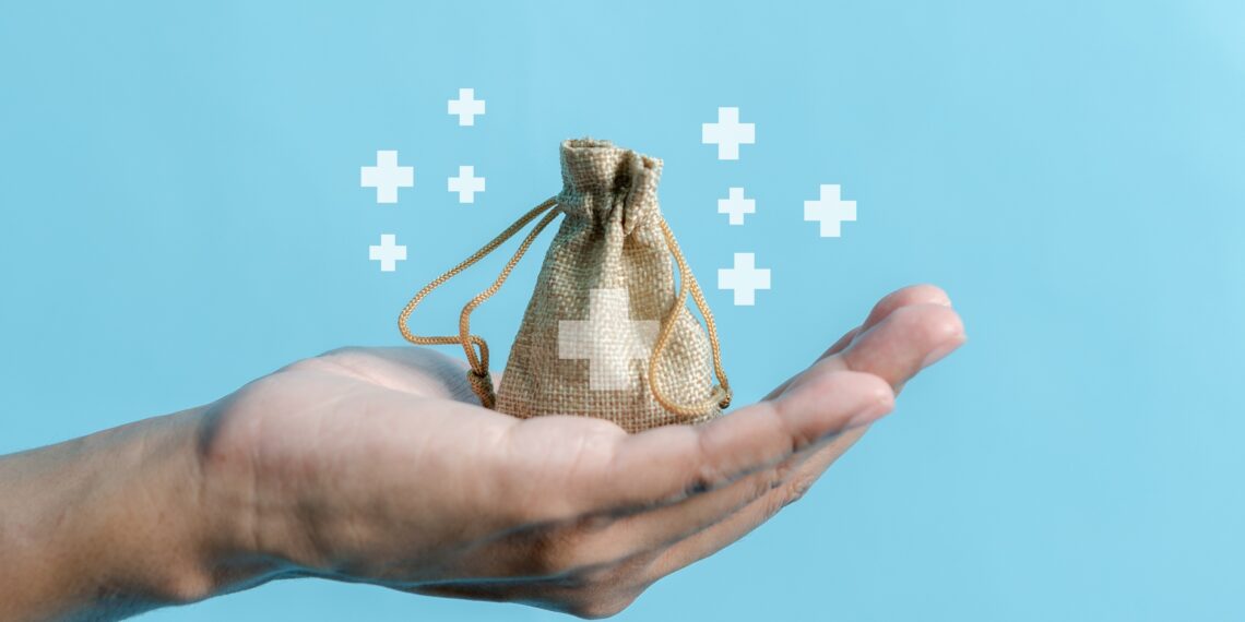 Mano sostiene bolsa de tela con símbolo de salud, ilustrando conceptos de costos médicos.