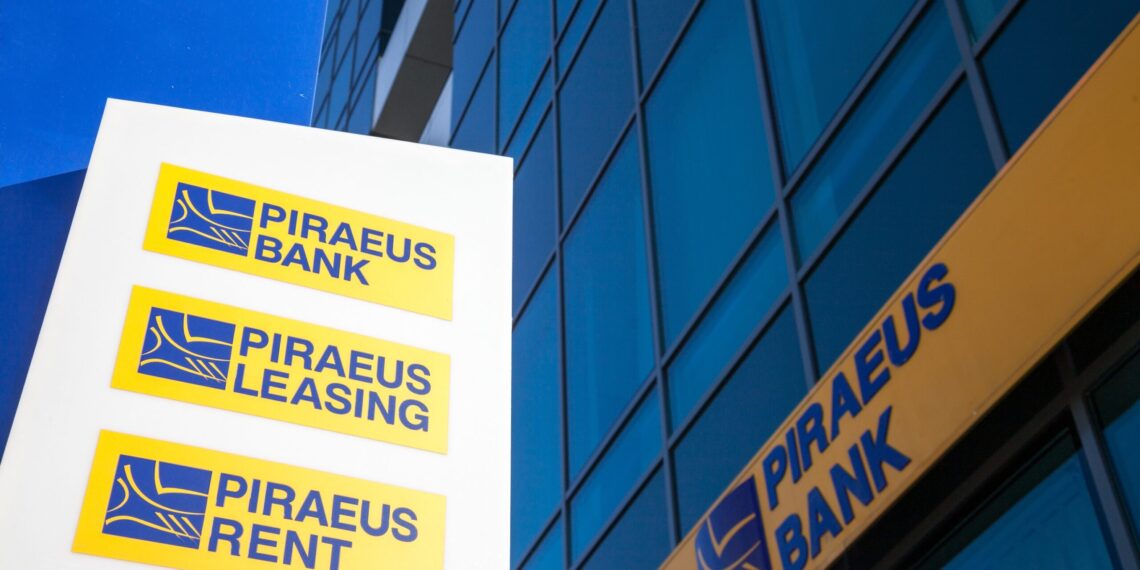 Logotipo de Piraeus Bank en edificio corporativo en Grecia, ilustrando la adquisición de Ethniki Insurance autorizada por la Comisión Helénica de Competencia.