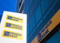 Logotipo de Piraeus Bank en edificio corporativo en Grecia, ilustrando la adquisición de Ethniki Insurance autorizada por la Comisión Helénica de Competencia.