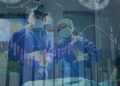 Médicos en quirófano con gráficos financieros superpuestos, ilustrando el impacto de las pandemias en la industria de seguros y en la gestión global de riesgos.