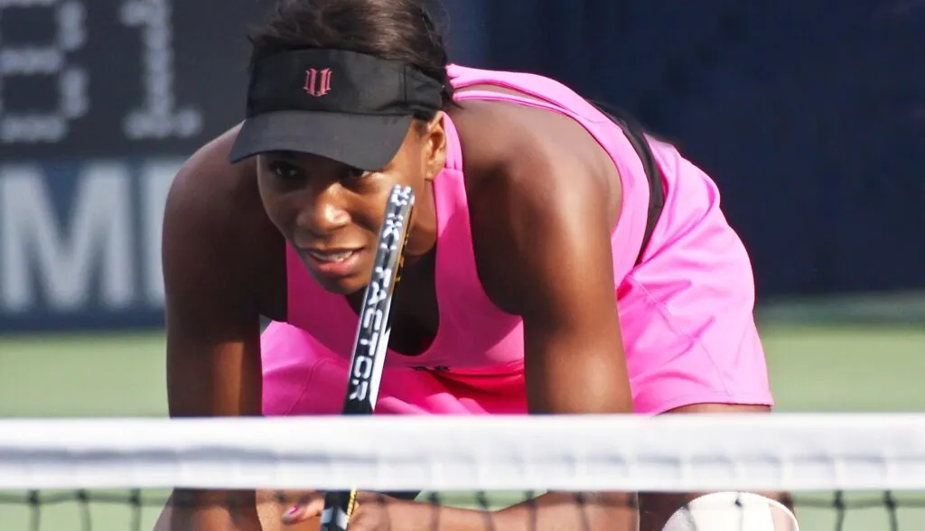 Venus Williams concentrada durante un partido de tenis, representando su experiencia con seguros médicos en Estados Unidos, incluidos COBRA y la ACA, y las dificultades de acceso a tratamientos de salud.