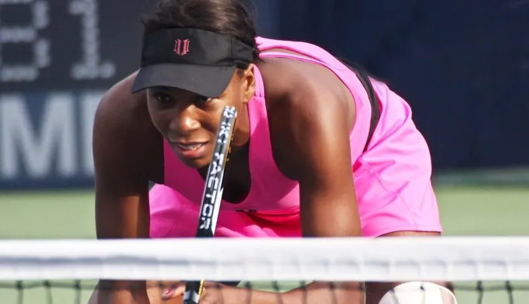 Venus Williams concentrada durante un partido de tenis, representando su experiencia con seguros médicos en Estados Unidos, incluidos COBRA y la ACA, y las dificultades de acceso a tratamientos de salud.