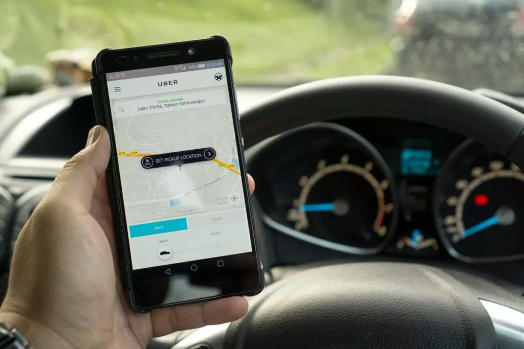 Conductor de Uber en México frente al volante mostrando la aplicación móvil y la importancia de contar con seguro especializado.