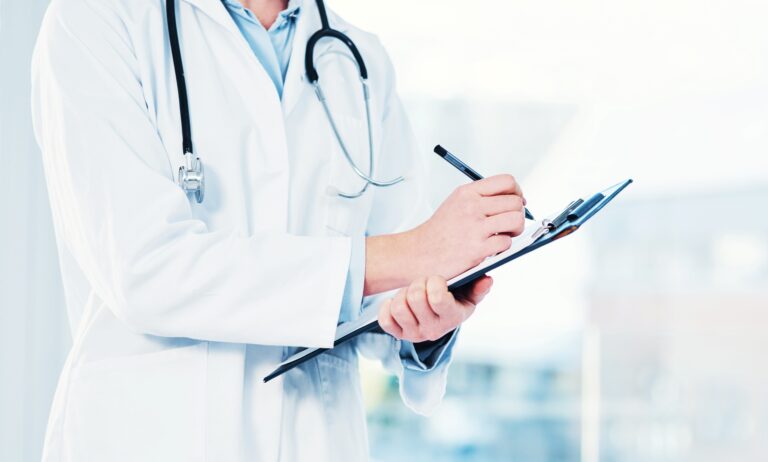Médico con bata blanca y estetoscopio escribe en portapapeles, ilustrando atención profesional en seguros médicos