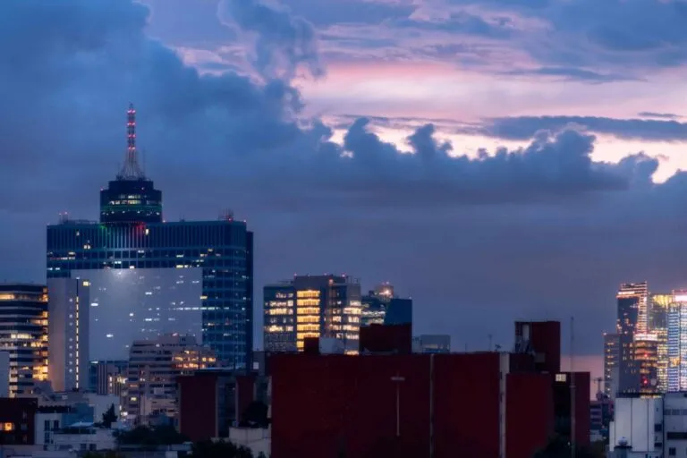 Fotografía editorial de un edificio corporativo mexicano con gráficos que representan riesgos y protección financiera, transmitiendo seguridad empresarial y resiliencia.