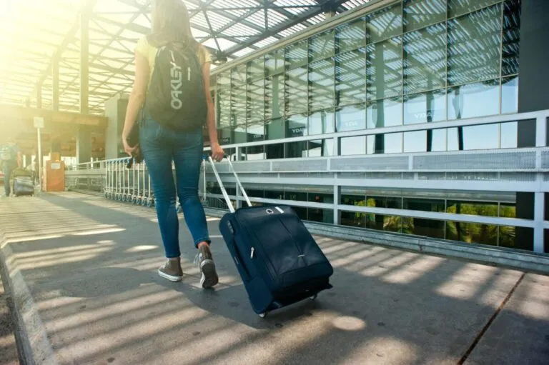 Mujer caminando con maleta en un aeropuerto internacional, relacionada con el crecimiento del mercado saudí de seguro de viajes y soluciones digitales