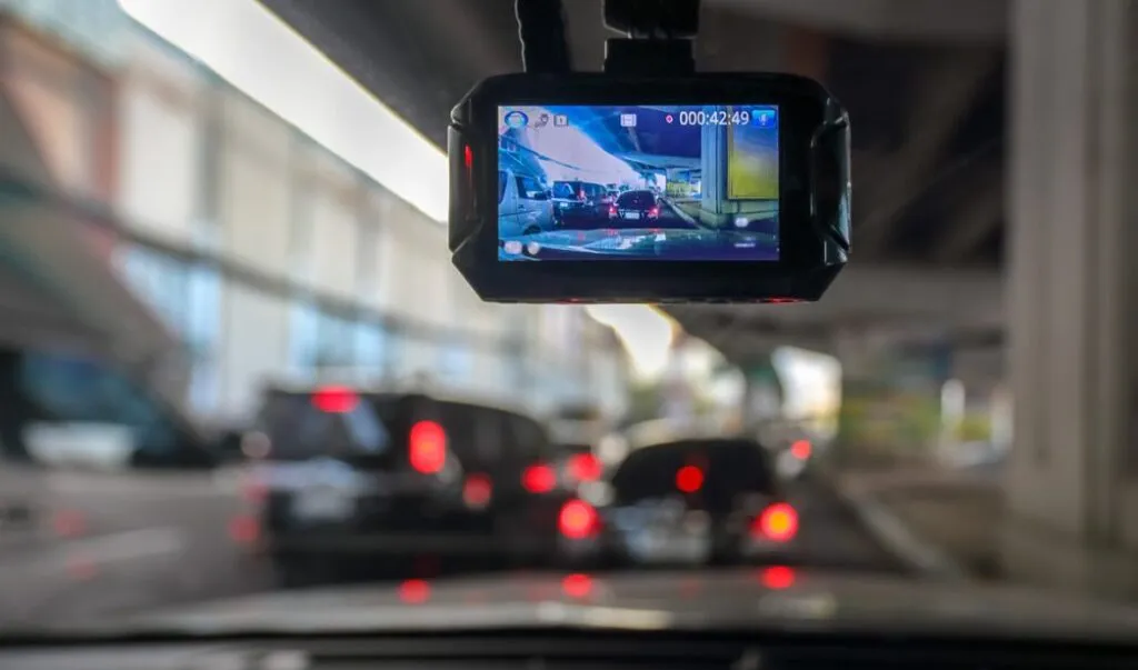 Dashcam instalada en el parabrisas de un coche grabando el camino como posible evidencia para seguro.