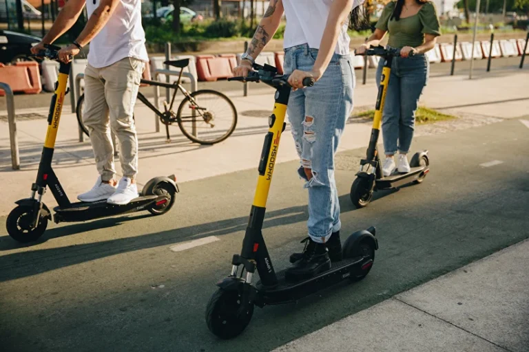 Usuario circula en patinete eléctrico con casco y equipo reflectante en una calle urbana, representando patinetes eléctricos seguros