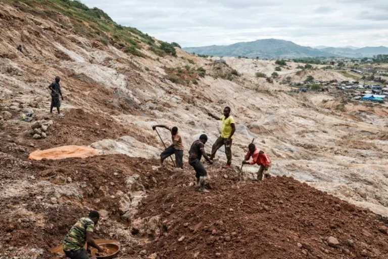 Fotografía de mineros en el Congo trabajando en terreno accidentado, reflejando impacto de violencia política en seguros