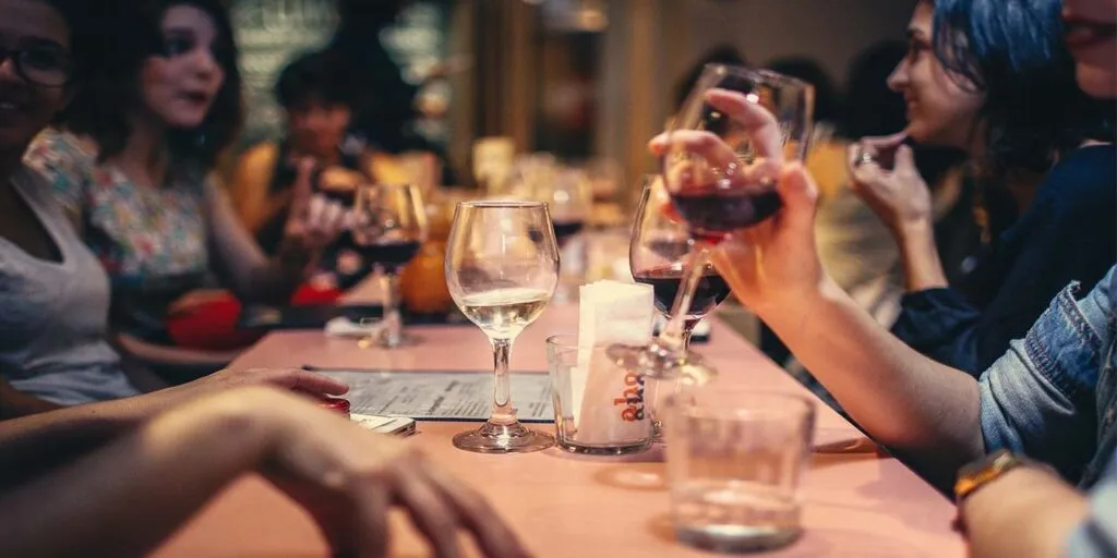 Anfitrión sirviendo licor en evento social con símbolo de protección de seguro de responsabilidad civil